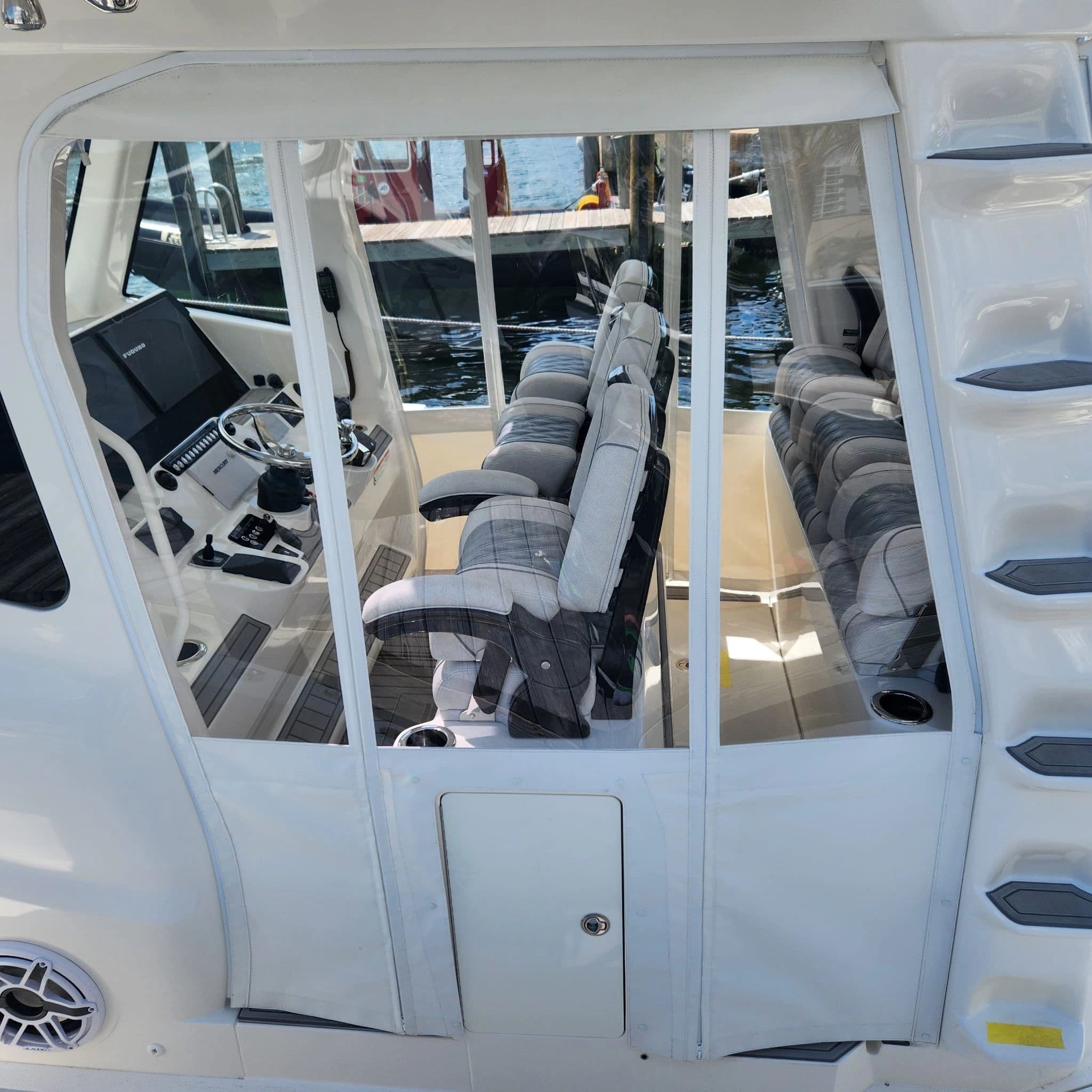Clear enclosure panels around a boat helm with upholstered seating — Canvas Craft's own work
